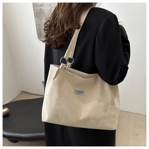 Detailed texture of beige corduroy tote bag with Fashion Instinct label and metal rings