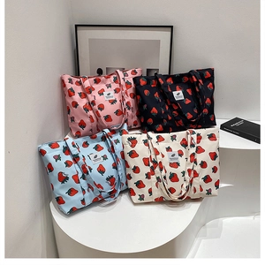 Detail of four colorful strawberry print canvas tote bags on a minimalist display stand