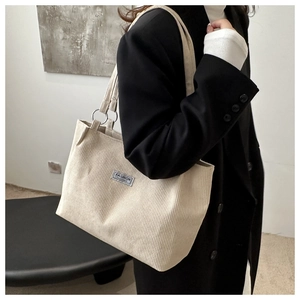 Detail of corduroy texture and silver metal rings on a beige crossbody tote bag