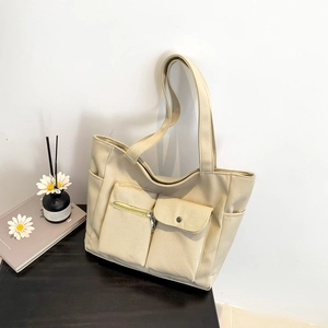 Large beige canvas tote bag with multiple pockets and functional zippers for daily commuting