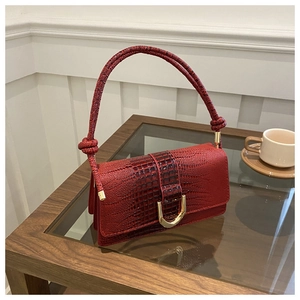 Detail of red croc-effect handbag with gold U-clasp and braided knot handle