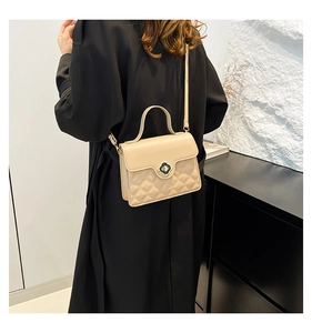 Detail of beige quilted shoulder bag featuring a floral gold-tone twist lock and thin strap
