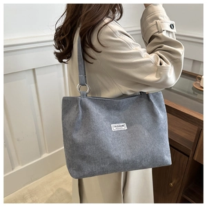 Detail of grey corduroy tote bag showing metal ring strap and fashion logo tag