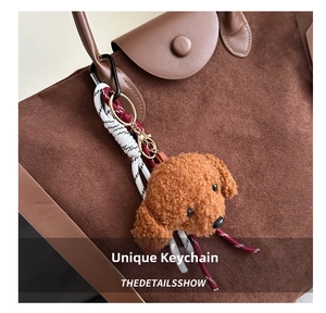 Détail d'un charm chien en peluche marron sur l'anse d'un sac cabas en daim