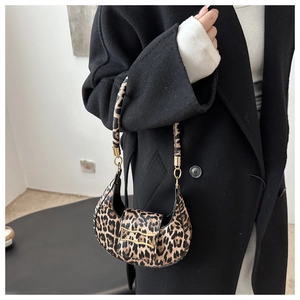 Detail of leopard print crescent bag with gold buckle paired with a black winter coat