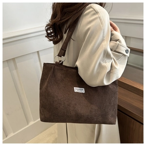 Detail of corduroy texture and metal ring connection on a dark brown tote bag