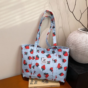 Fresh light blue strawberry print tote bag on a wooden table with natural background