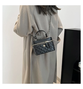 Rear view of model wearing a black quilted leather chain bag with camellia ornament