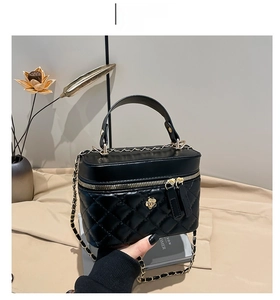 Close-up of quilted black crossbody bag with golden chain and floral charm detail