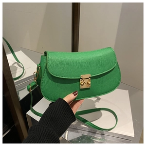 Detail of green lychee leather texture and golden metal lock on a crossbody bag