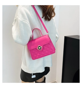 Detail of magenta leather handbag featuring quilted pattern and floral gold-tone clasp