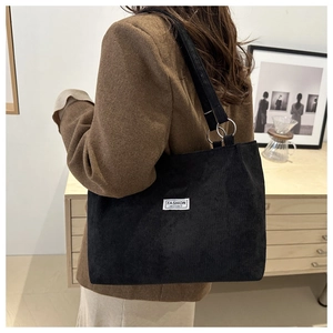 Detail of black corduroy tote bag with metal rings and Fashion Instinct woven label