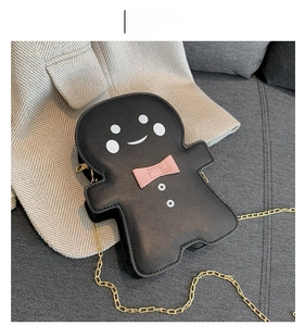 Close-up of ginger man shaped crossbody bag in black with golden chain and pink bow
