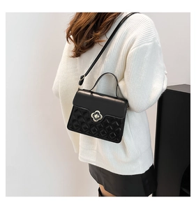 Detail of black quilted crossbody bag featuring a vintage golden floral twist lock