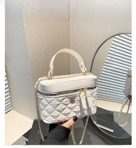 Close-up of a white quilted bucket bag featuring a gold floral clasp and metal chain strap