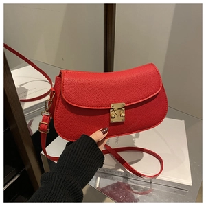 Detail of red saddle bag featuring litchi texture leather and gold metal buckle