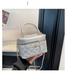 Silver quilted bucket bag featuring a floral metal clasp and elegant chain shoulder strap
