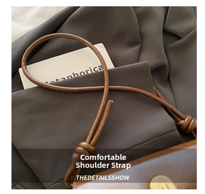 Detail of vintage brown PU leather bag showing adjustable knotted strap and gold metal lock