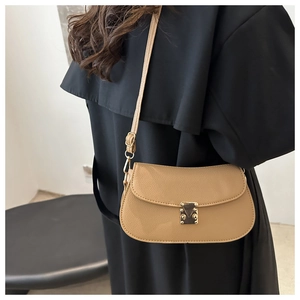 Close-up of khaki litchi grain leather crossbody bag with golden metal buckle on black coat