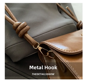 Detail of the high-quality gold hardware hook and knotted strap on a brown leather bag