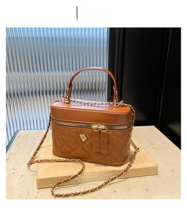 Detail of brown quilted leather crossbody bag with camellia buckle and gold chain strap