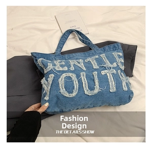 Detail of light blue denim tote bag with frayed GENTLE YOUTH letter patchwork design