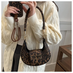 Detail of leopard print shoulder bag with golden geometric clasp and textured fabric