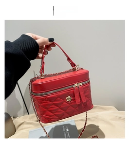 Macro detail of red quilted leather handbag with golden flower hardware and chain strap