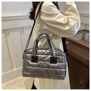 Detail of silver quilted puffer bag featuring metallic finish and wide shoulder strap
