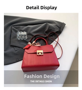 Dettaglio borsa rossa in ecopelle con chiusura dorata e foulard decorativo in seta nera