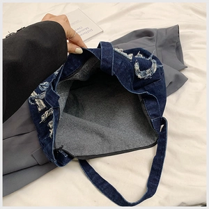 Close-up of denim tote bag showing frayed edge details and spacious interior opening