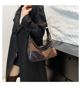 Detail of hobo shoulder bag featuring two-tone brown patchwork and glossy pleated leather