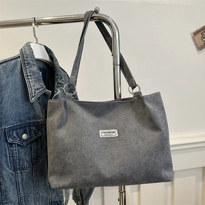 Minimalist grey corduroy tote bag with fashion label and silver metal ring straps