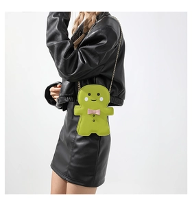 Close-up of green gingerbread man shaped crossbody bag with gold chain and pink bow details