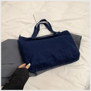 Detail of dark blue denim tote bag showing twill texture and retro distressed finish