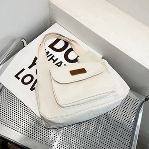 Minimalist cream canvas tote bag with front pocket on a silver chair for commute