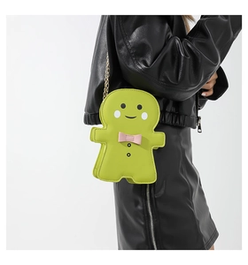 Close-up of a lime green gingerbread man crossbody bag with pink bow and gold chain strap