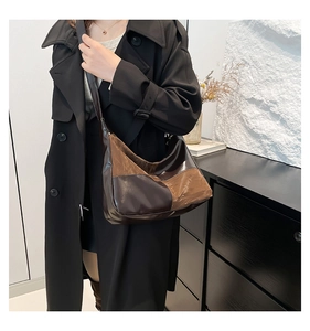 Close-up of a two-tone crossbody bag with pleated texture worn on a model's shoulder