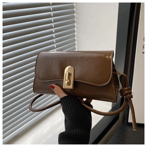 Close-up of vintage dark brown baguette bag featuring a gold lock and knotted shoulder strap
