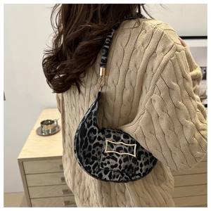 Detail shot of leopard print crescent bag on shoulder with metallic buckle closure
