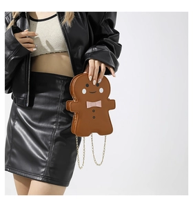 Detail of gingerbread man crossbody bag with pink bow and gold chain on model