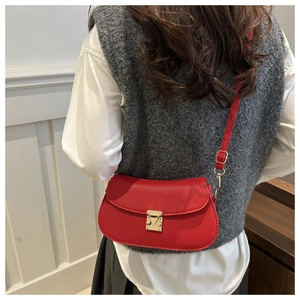 Detail of red lychee grain leather crossbody bag with elegant gold push-lock closure