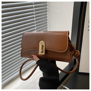 Detail of vintage brown leather bag with golden metal lock and stylish side knot strap