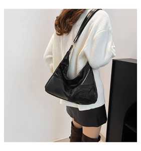 Close-up of black glossy hobo bag in high-shine leather with minimalist side stitching