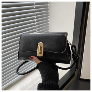 Close-up of black pleated faux leather bag with gold rectangular buckle and knot detail