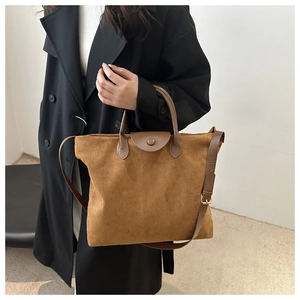 Dettaglio di una borsa tote in pelle scamosciata marrone con patta e tracolla regolabile
