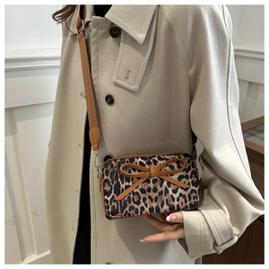 Close-up of leopard print square crossbody bag with a brown bow and adjustable strap