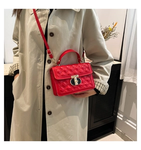 Detail view of red quilted leather handbag with gold twist lock and elegant stitching
