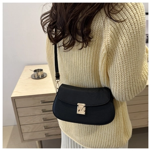 Close-up of black lychee texture leather shoulder bag with gold metal clasp on model