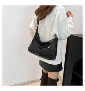 Detail of black faux leather tote bag with adjustable strap on a female model